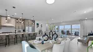 Une cuisine moderne avec un coin bar, un espace repas avec une table pour quatre personnes et un salon offrant une vue sur le port de plaisance.