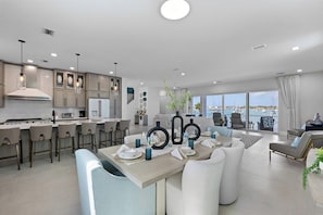 Una cocina moderna con barra, comedor con mesa dispuesta para cuatro personas y sala de estar con vista al puerto deportivo.