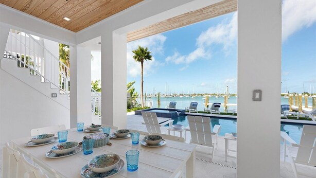 Un espace repas avec vue sur un port de plaisance et une piscine.