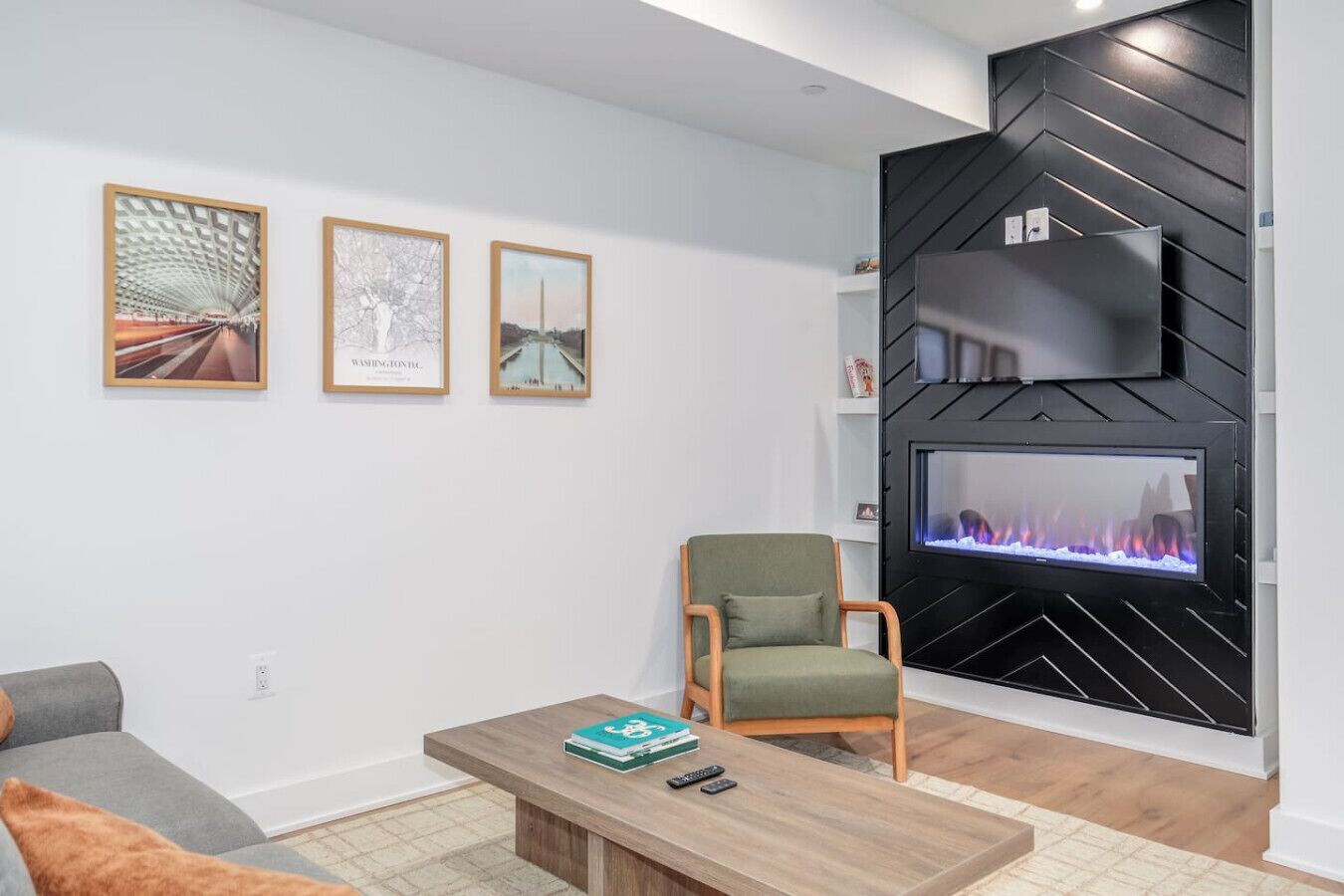 A modern living room with a fireplace, a sofa, a coffee table, and framed pictures on the wall.