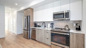 Une cuisine moderne équipée d’appareils électroménagers en acier inoxydable, d’un four à micro-ondes et de meubles en bois.