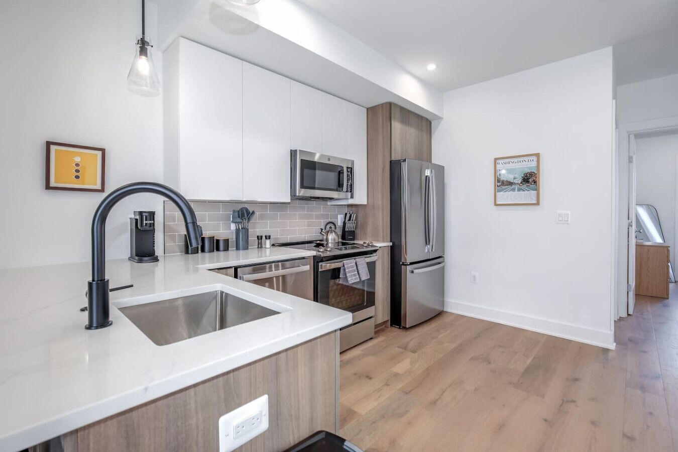 Una cocina moderna con armarios blancos, electrodomésticos de acero inoxidable y suelo de madera.