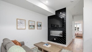A modern living room with a sofa, coffee table, and a black wall unit with a fireplace.