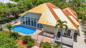 Una casa de dos pisos con piscina, ventanas amplias y un porche cubierto.