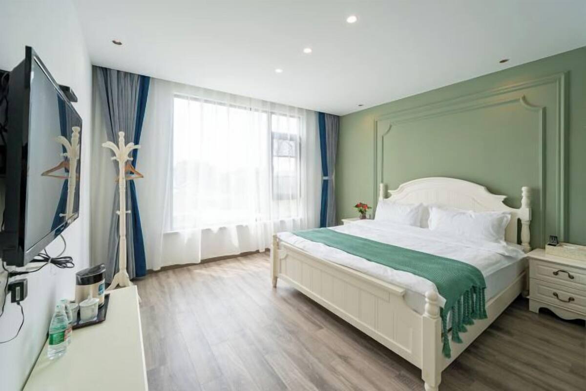 Une chambre d’hôtel avec un lit, une table de chevet, une télévision et une fenêtre avec des rideaux.