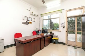A reception area with a wooden desk, two red chairs, a computer, and a trash bin. - Shanghai Dazaotou Homestay (Shanghai)