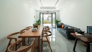 Una sala de reuniones moderna con una mesa de madera, sillas, un sofá y un ordenador portátil sobre un escritorio.