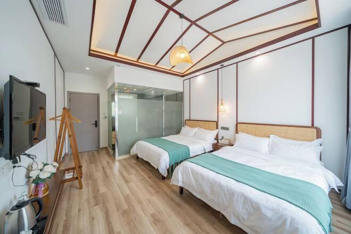 Une chambre d’hôtel avec deux lits, un téléviseur, un chevalet et vue sur le couloir.