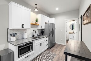 A modern kitchen with white cabinets, a stainless steel refrigerator, and a granite countertop.