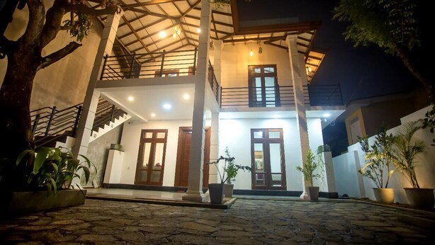 A two-story building with a covered entrance, potted plants, and a stone-paved courtyard.