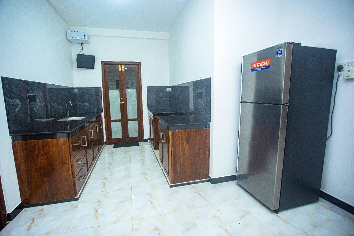Una cocina con armarios de madera, un refrigerador de acero inoxidable y piso de baldosas de mármol.