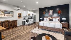 Una camera d'albergo moderna con un letto grande, un tavolo da pranzo in legno, angolo cottura e zona living.