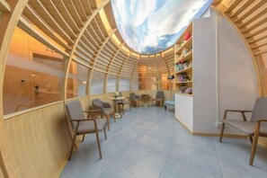 A modern interior with a curved ceiling, wooden slats, and a central seating area with tables and chairs. - Bolianhui Hotel (Chongqing Southwest Hospital) (Chongqing)