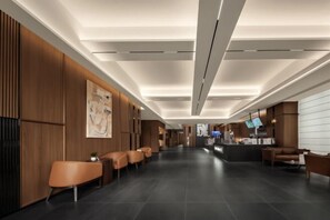 Un hall d’hôtel moderne avec un comptoir d’accueil, un espace salon et des œuvres d’art accrochées aux murs.