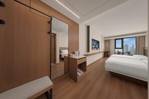 Une chambre d’hôtel moderne, dotée d’un grand lit, d’un bureau, d’un miroir et offrant une vue sur la ville.