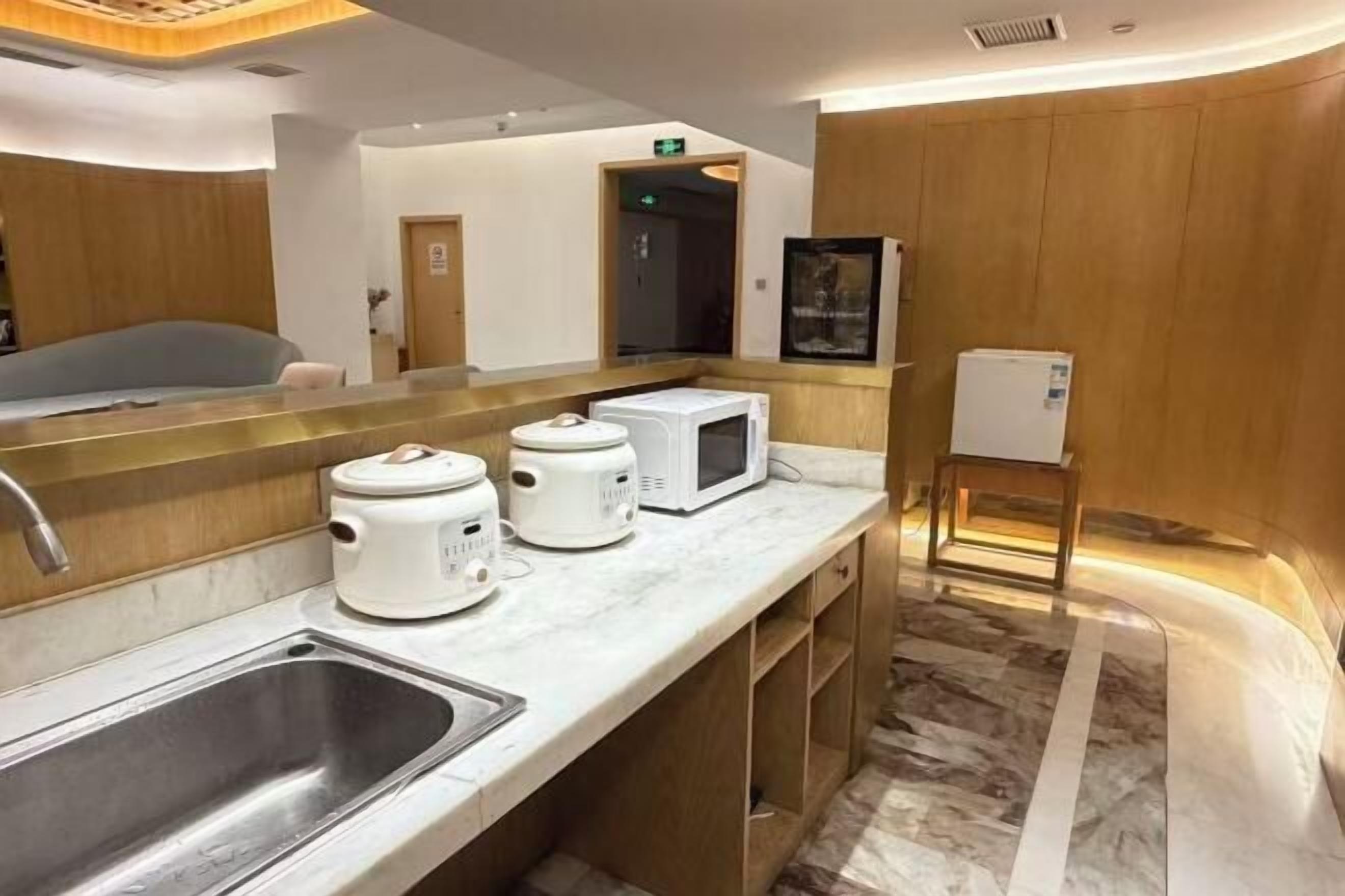 A modern kitchen with a marble countertop, a sink, and a microwave.
