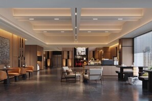 Eine moderne Hotelhalle mit einer zentralen Sitzecke, einer Bar und einer Küche im Hintergrund.