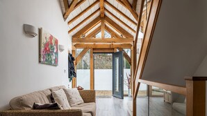 A cozy room with a high ceiling, a wooden ceiling, a sofa, a painting, and a door leading outside. - Sleeps 12, swimming pool, sea views, games rooms (Watermouth)
