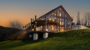 A modern house with a large glass facade, multiple levels, and a prominent balcony. - Sleeps 12, swimming pool, sea views, games rooms (Watermouth)