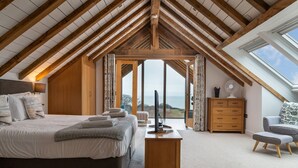 A bedroom with a large bed, a wooden dresser, a chair, and a desk with a computer. - Sleeps 12, swimming pool, sea views, games rooms (Watermouth)