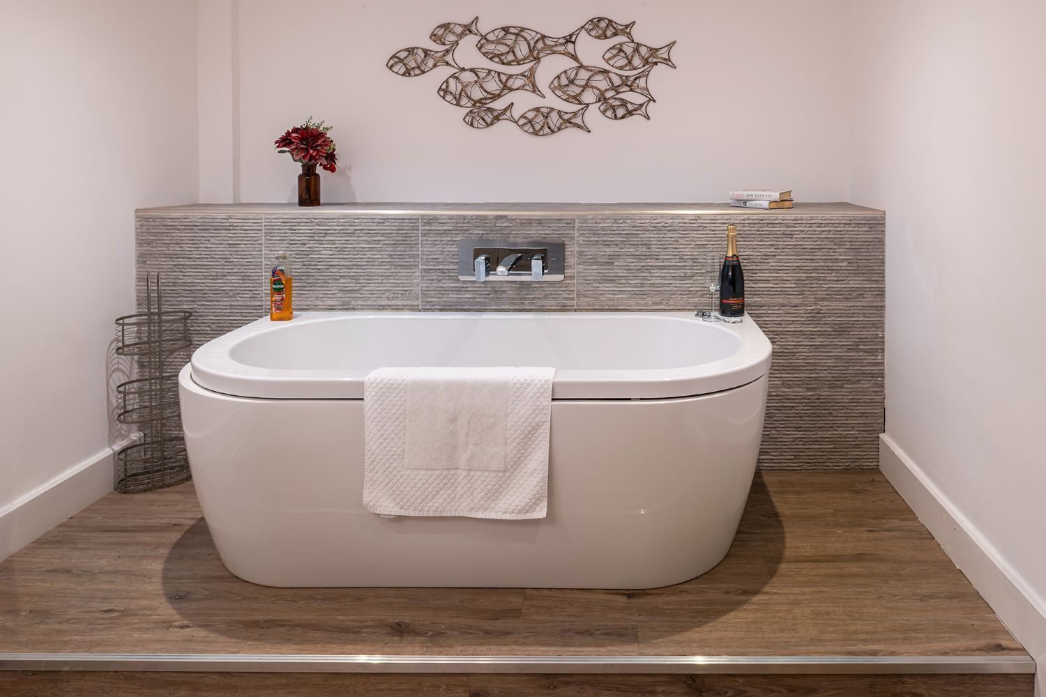 Une salle de bain moderne avec une baignoire sur pieds, une serviette, des toilettes et un élément décoratif mural.