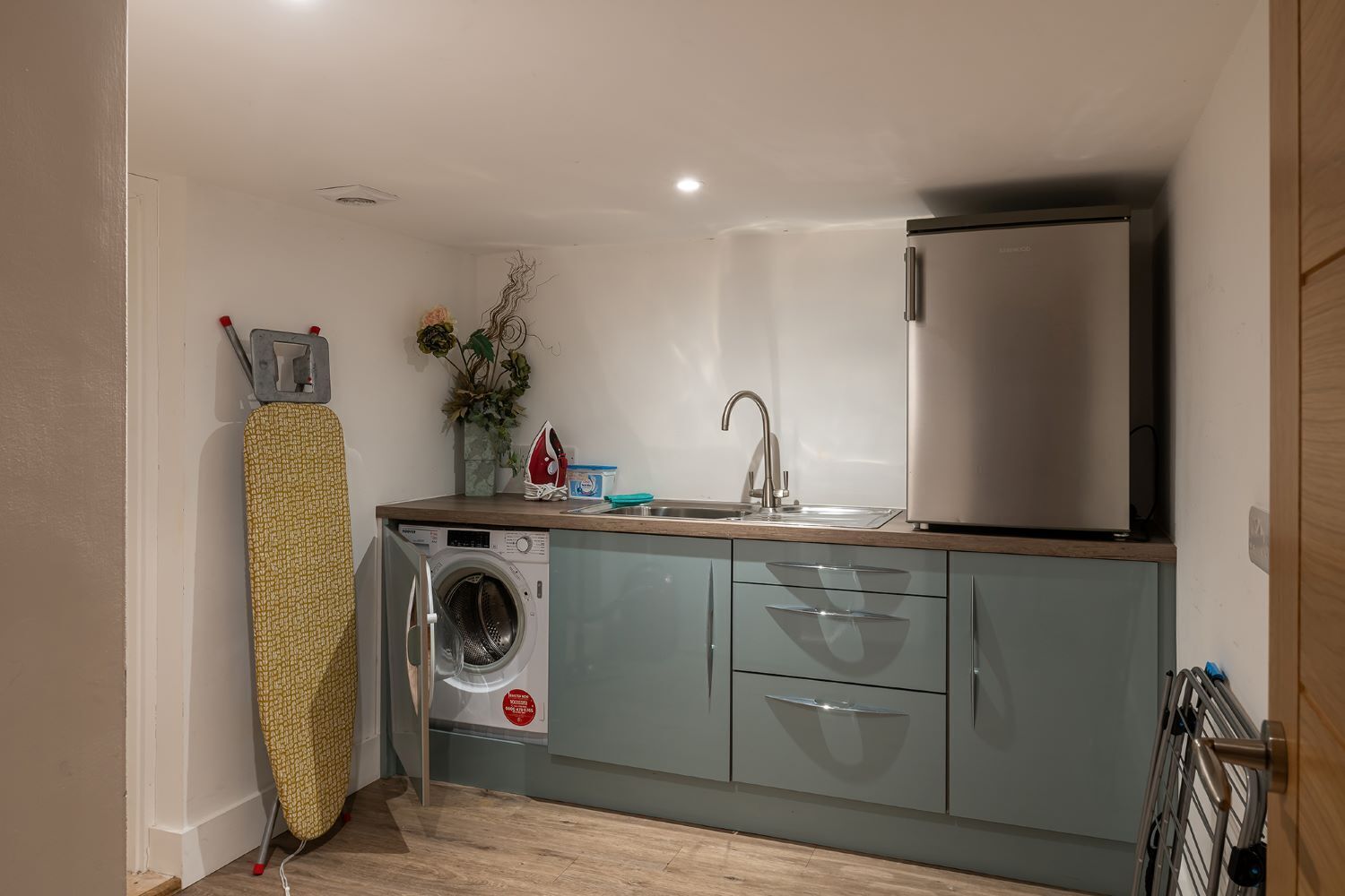 A compact kitchen with a washing machine, a sink, and a refrigerator.