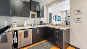 A modern kitchen with dark cabinets, stainless steel appliances, and a granite countertop. - Relaxing 2 BR  Beach & Pool  Condo Unit2 (Brasilito)