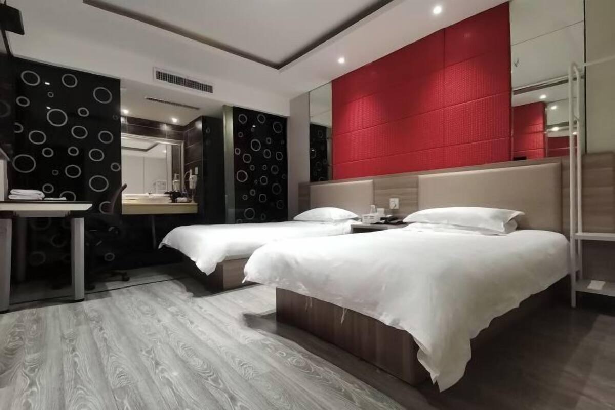 Una habitación de hotel moderna con dos camas, un escritorio y un espejo grande.