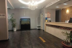 A hotel reception area with a reception desk, a chandelier, a potted plant, and a wall-mounted screen. - Margarita Boutique Hotel (Guangde)
