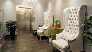 A lobby with a chandelier, two upholstered chairs, a potted plant, and an elevator. - Margarita Boutique Hotel (Guangde)