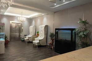 Un interior moderno con mostrador de recepción, dos sillones tapizados, un acuario y una televisión.