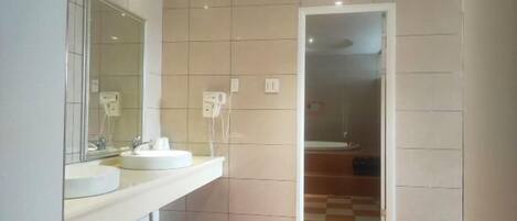 Un baño con dos lavamanos, un espejo y una zona de ducha.