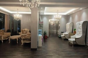 A hotel lobby with ornate chairs, a water dispenser, and a chandelier.