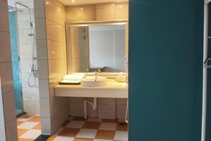 Uma casa de banho com chuveiro, lavatório e espelho.