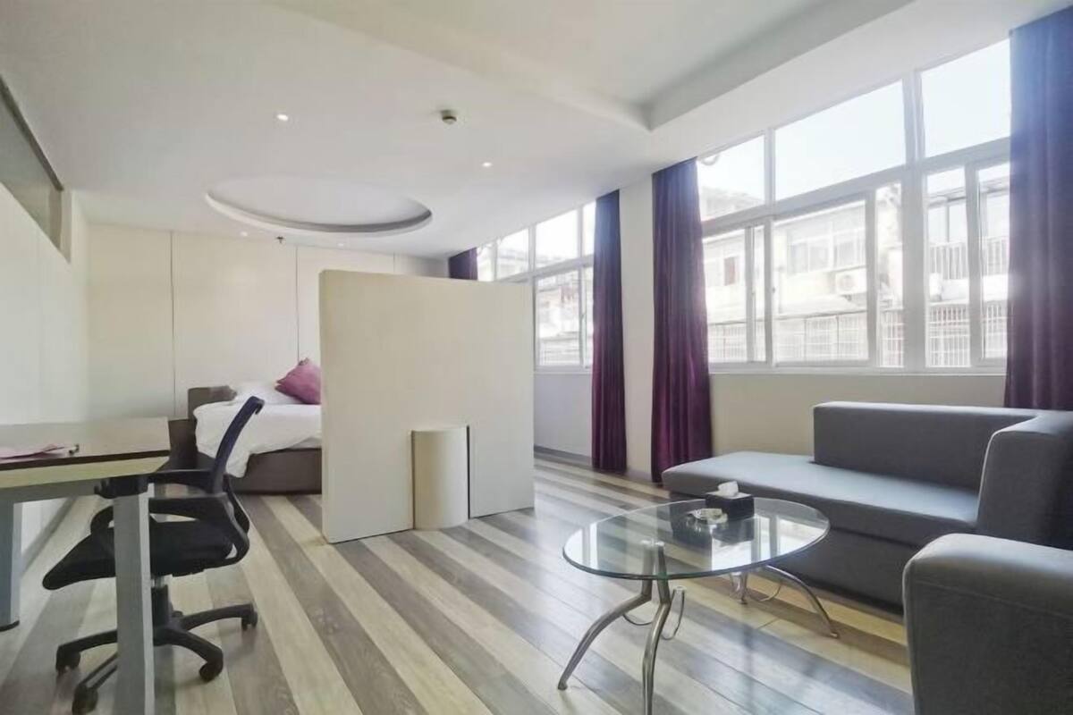 Una habitación de hotel moderna con una cama, un escritorio, una silla, un sofá y una mesa de vidrio.