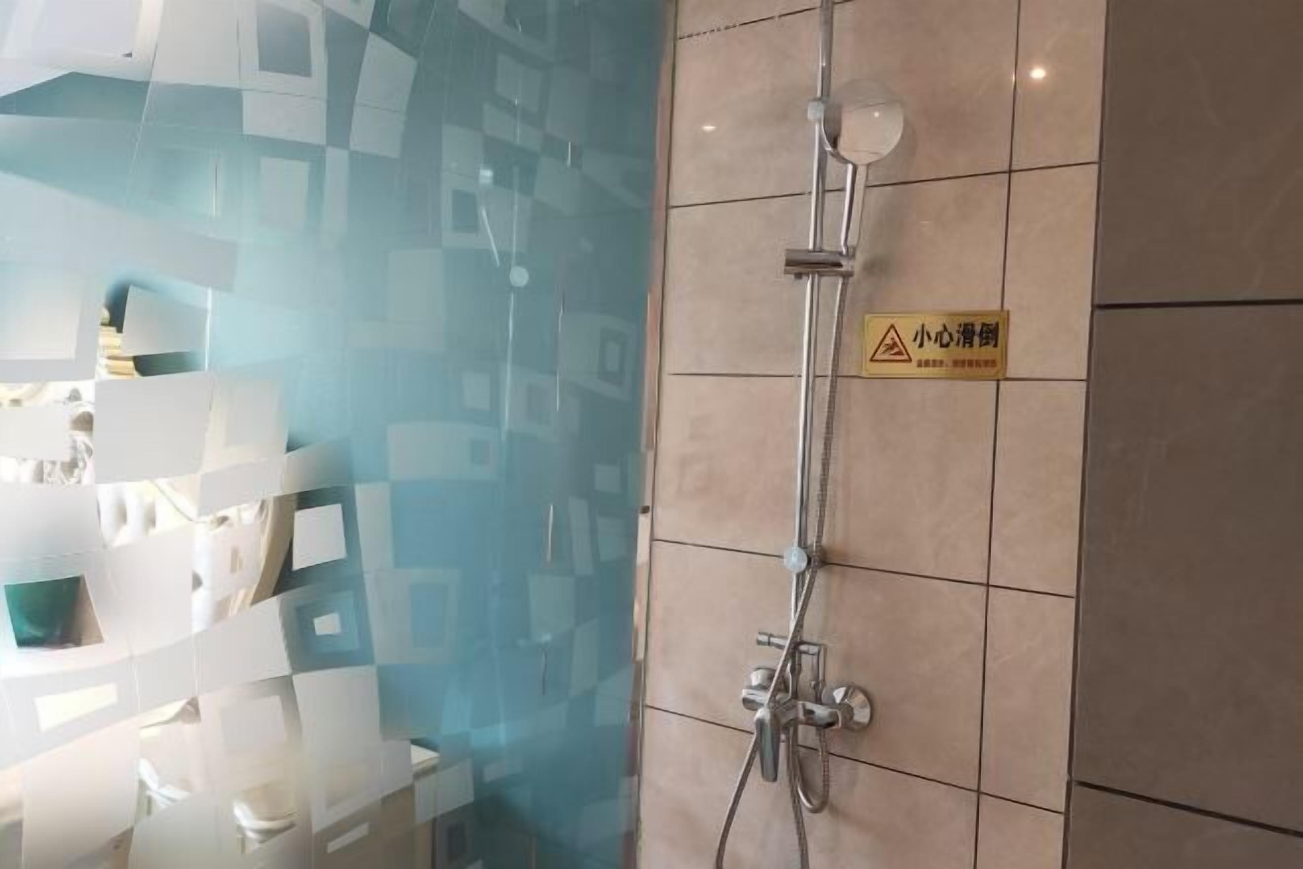 A shower with a glass partition and a warning sign in a bathroom.