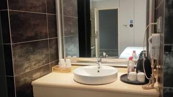 A modern bathroom with a round sink, a mirror, and a telephone.
