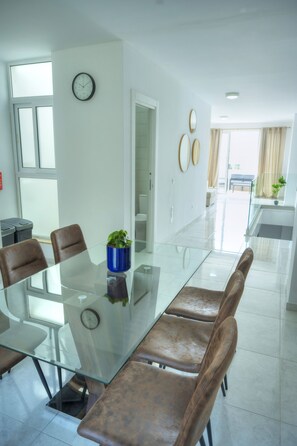 Un comedor moderno con una mesa de vidrio, sillas de cuero y una planta en maceta.