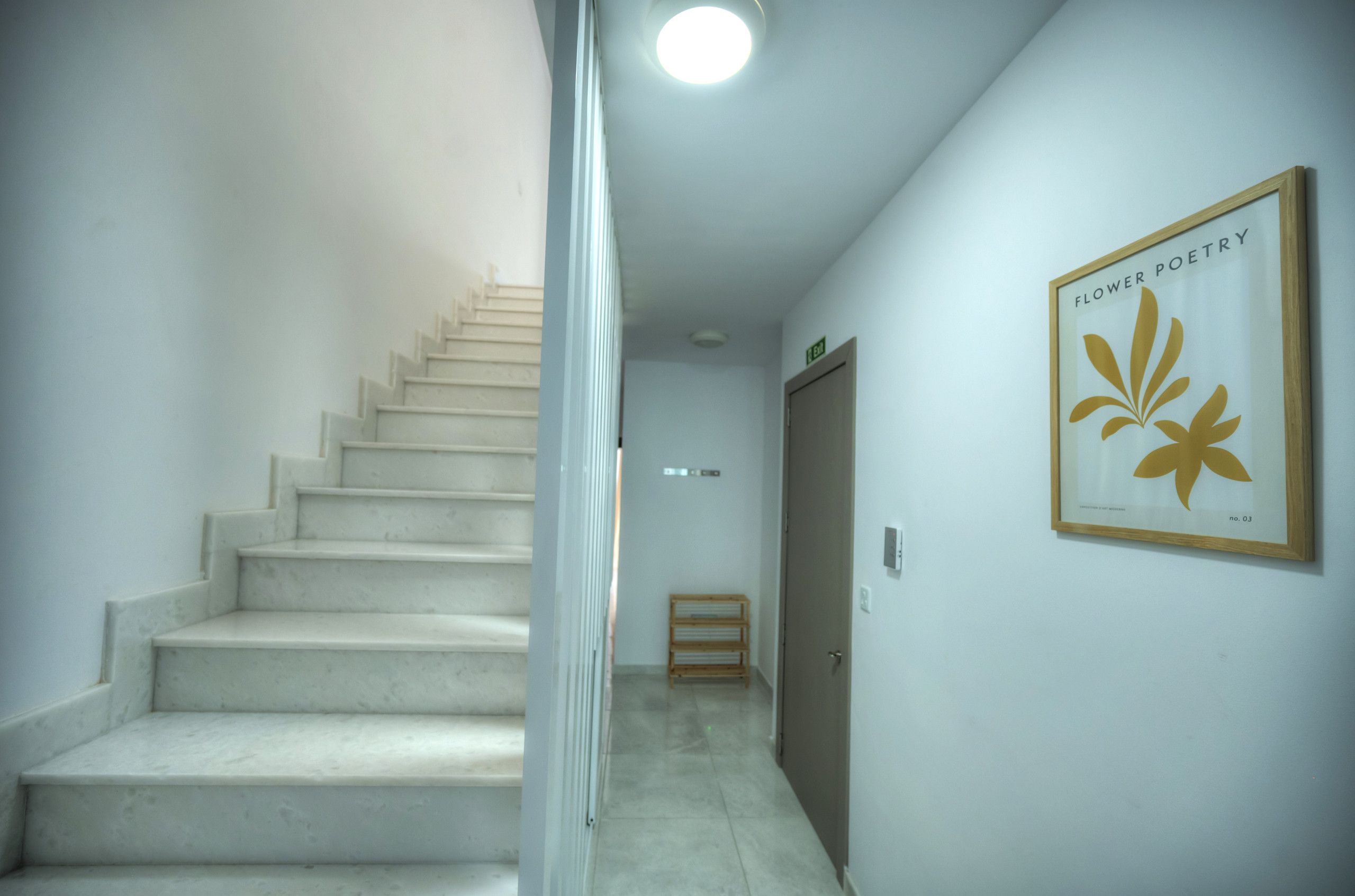 A staircase leading to a door with a framed picture of a flower.