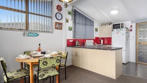 A compact kitchen with a dining area, featuring a central island, a refrigerator, and a microwave.