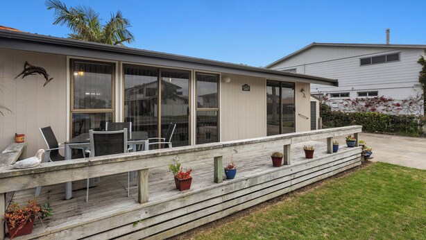 A house with a covered porch, outdoor seating, and potted plants.