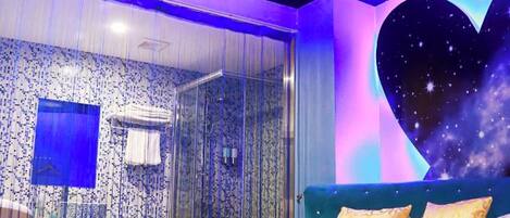 A bedroom with a bed, a shower, and a wall with a starry design.