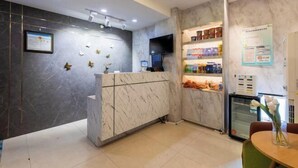 Un espace d’accueil doté d’un comptoir en marbre, d’un téléviseur et d’un réfrigérateur.
