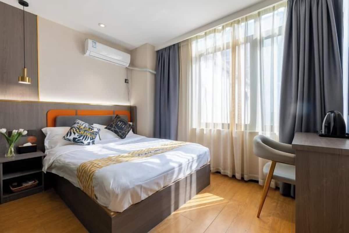 A hotel room with a bed, bedside table, and a desk with a chair.