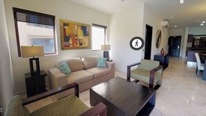 A living room with a sofa, armchairs, a coffee table, and a painting on the wall. - Ocean view 2nd floor, luxury 1 bedroom condo at EL FARO by DPM (Playa del Carmen)