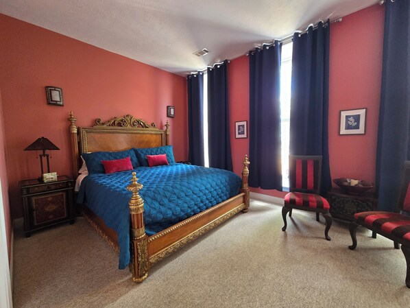 A bedroom with a large bed, a nightstand, a chair, and a window with curtains. - Natchez Manor Bed & Breakfast (Natchez)