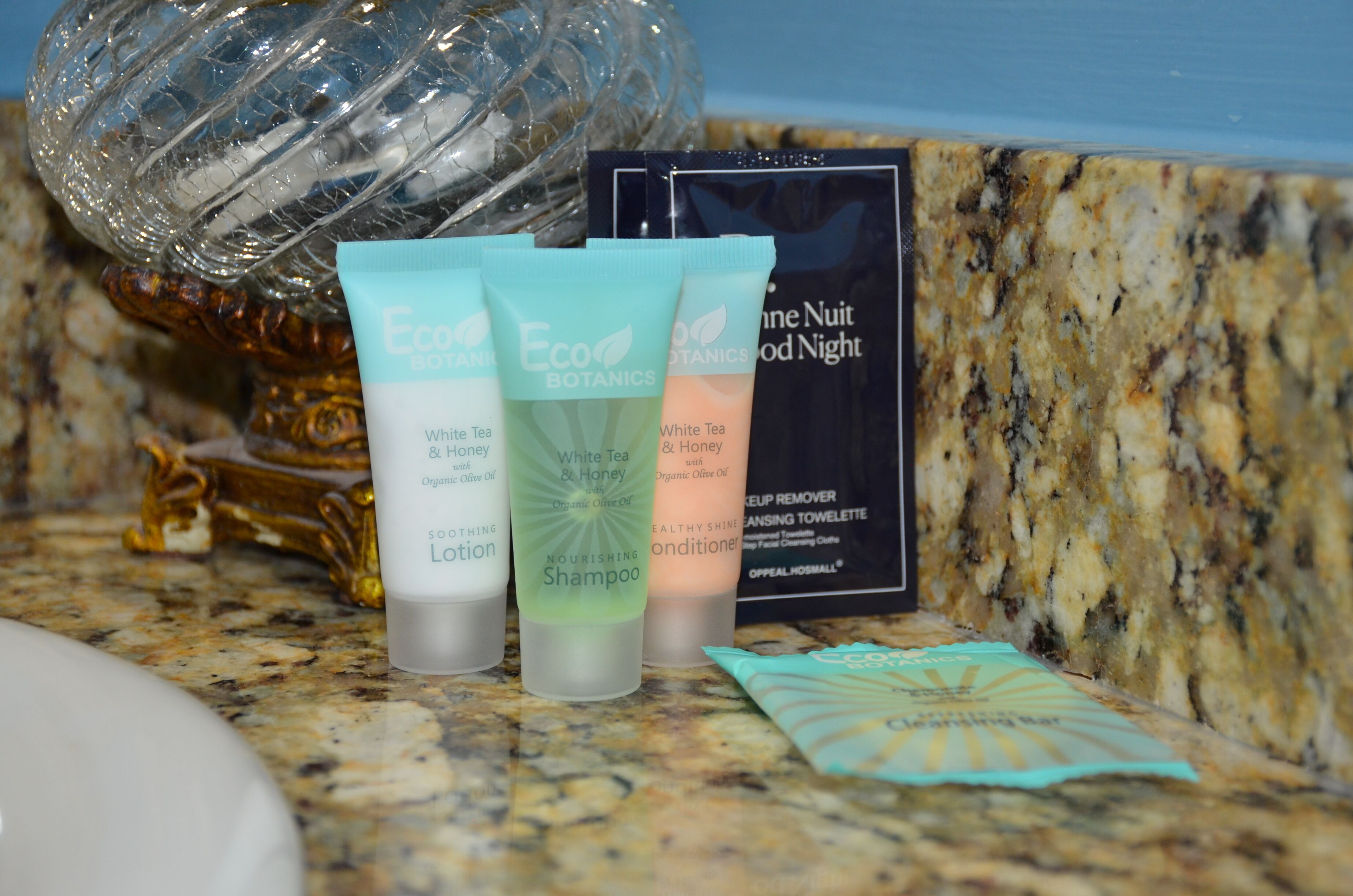 Una encimera de baño con tres productos Eco Botanics: una loción, un champú y una toalla limpiadora.