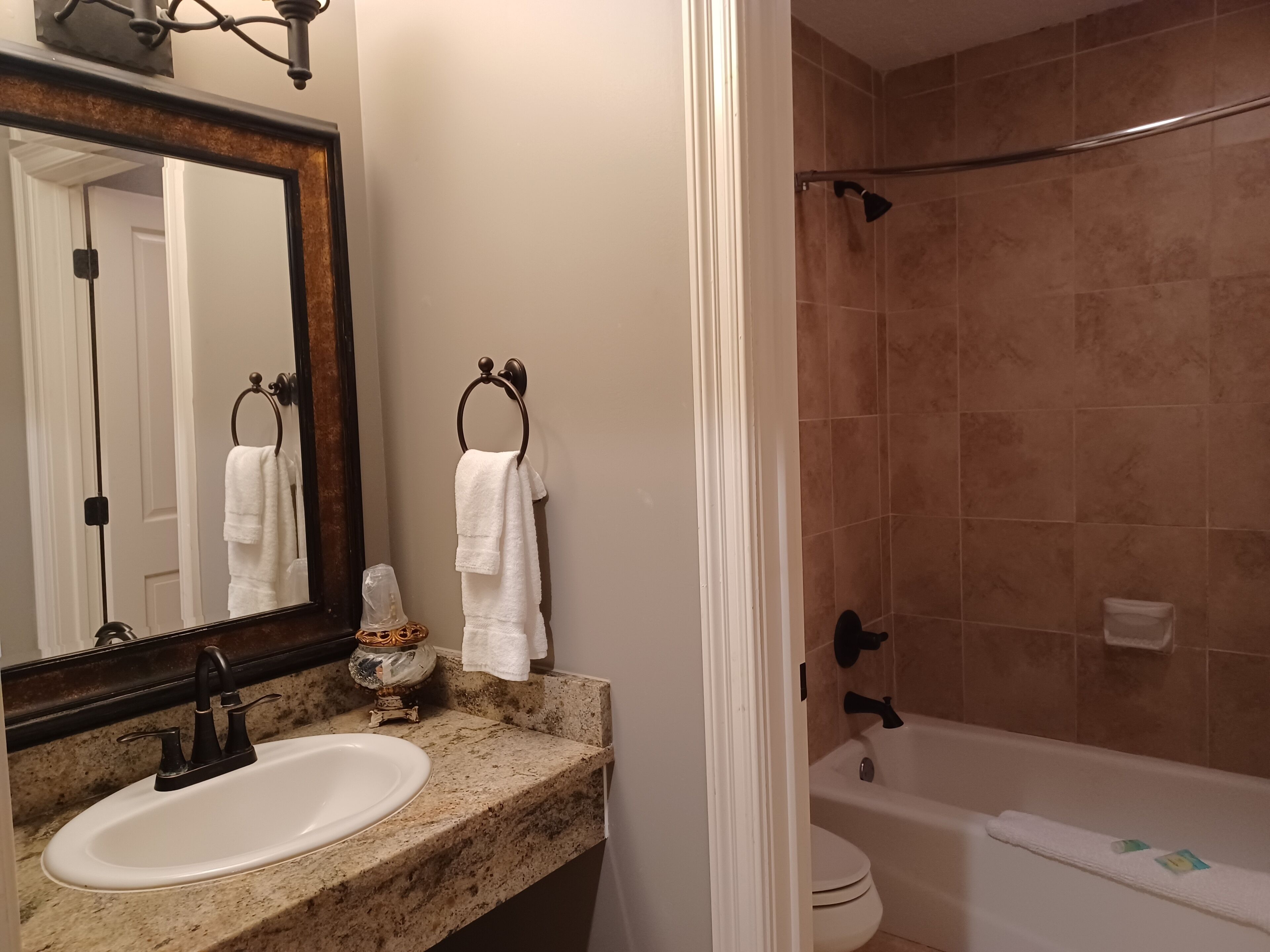 A bathroom with a sink, mirror, towel rack, shower, and toilet.