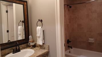 A bathroom with a sink, mirror, towel rack, shower, and toilet.