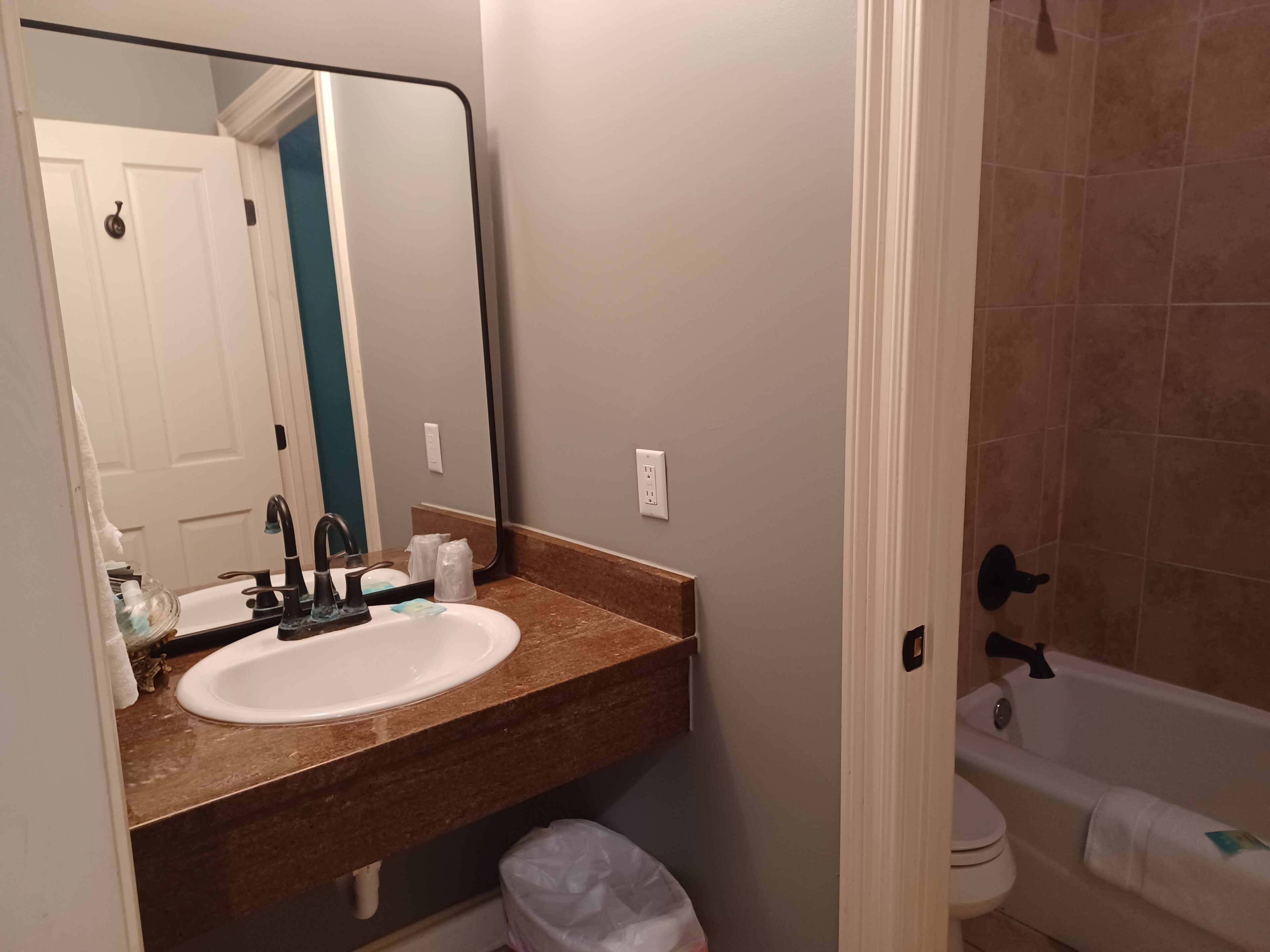 Une salle de bain avec un lavabo blanc, un miroir, une serviette, des toilettes et une baignoire.
